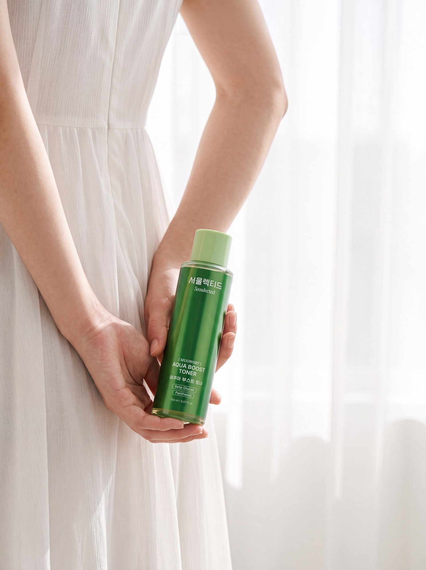 A woman in white holding the Aqua Boost Toner by a sunlit window